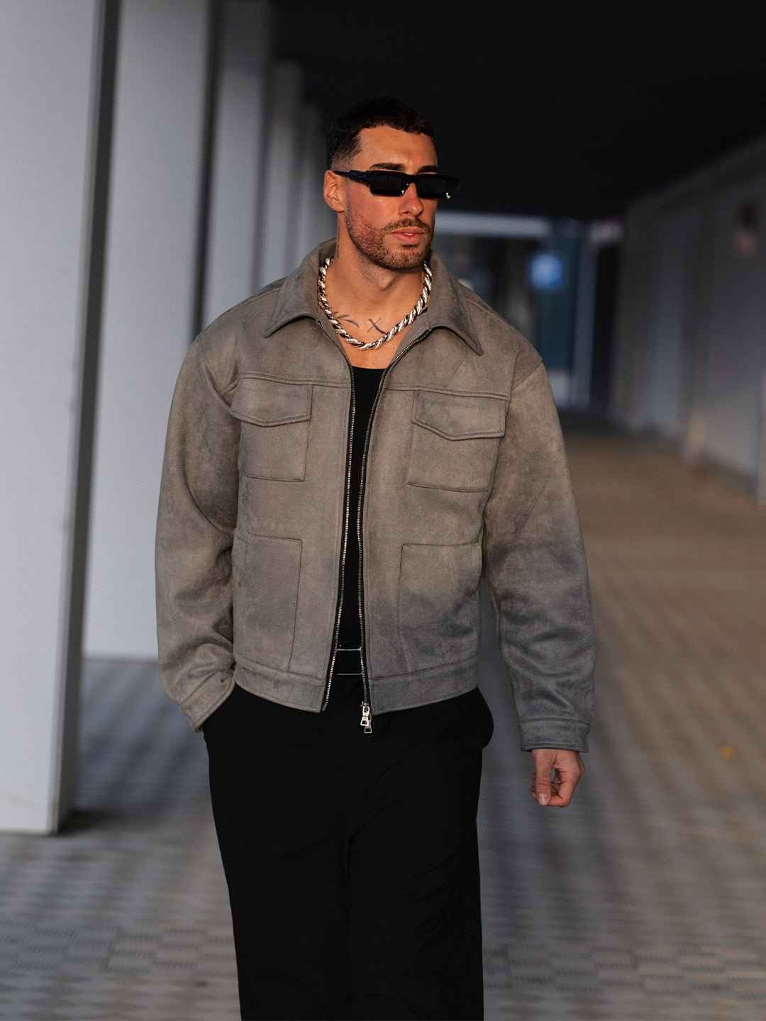 Man wearing Hipok Brand grey suede jacket with zipper and chest pockets walking outdoors